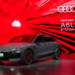 2026 Audi A6 e-tron Sportback electric sedan in gray parked at a charging station showing LED headlights and aerodynamic design